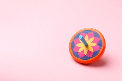 Photo of One colorful spinning top on pink background, space for text