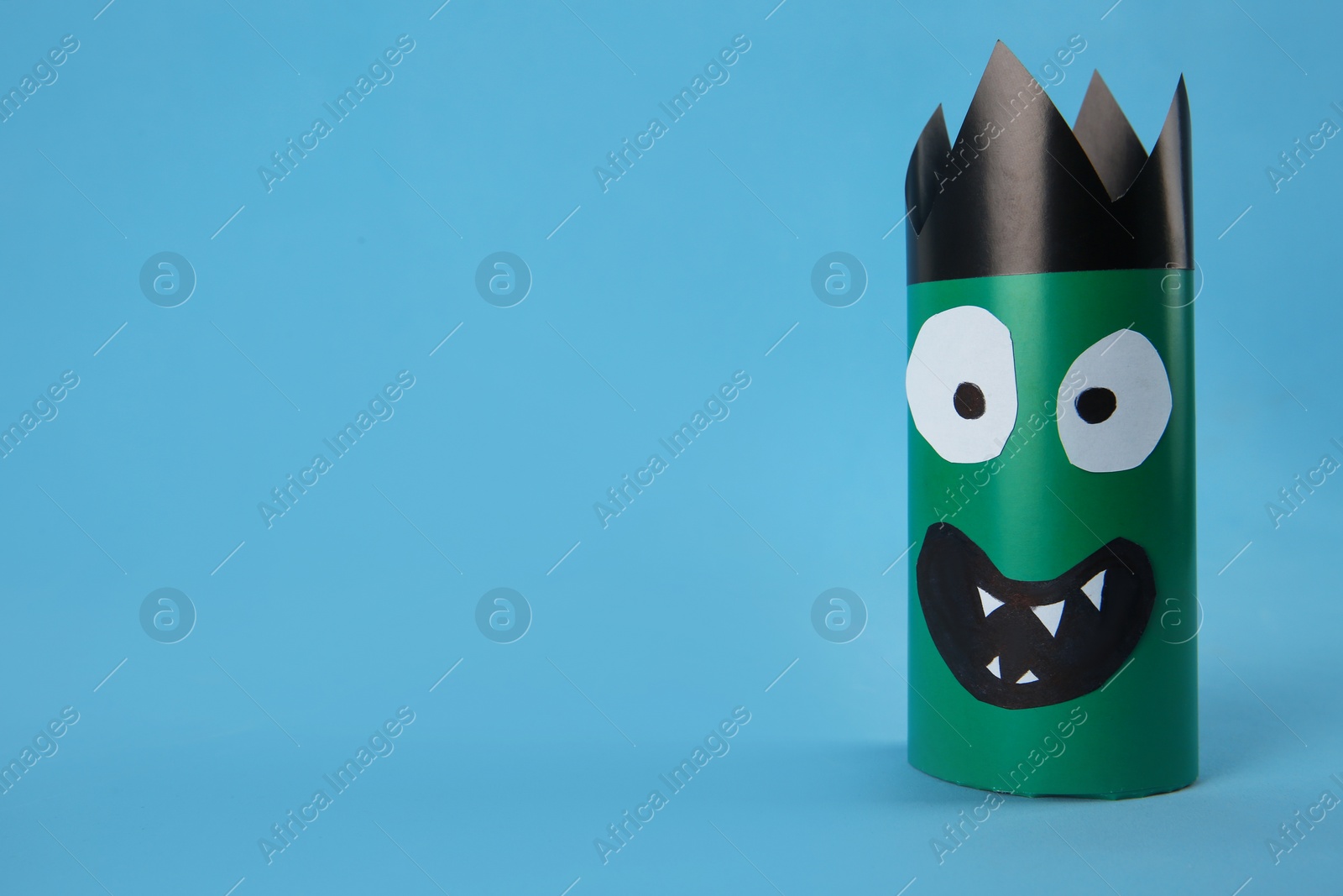 Photo of Funny green monster on light blue background, space for text. Halloween decoration