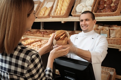 Photo of Woman buying tasty pastry in bakery shop