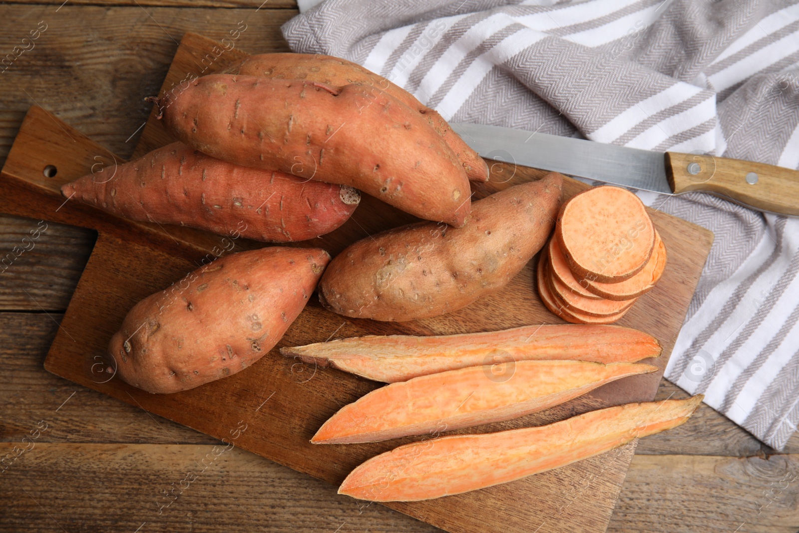 Photo of Sweet potatoes and knife on wooden table, flat lay