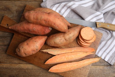 Photo of Sweet potatoes and knife on wooden table, flat lay