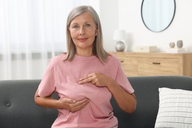 Photo of Beautiful senior woman doing breast self-examination at home