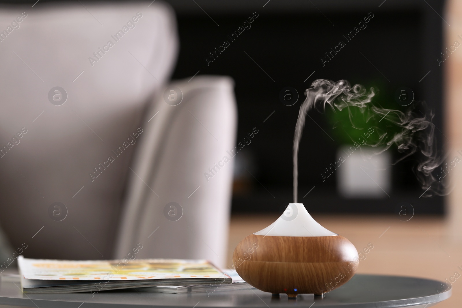 Photo of Aroma oil diffuser lamp on table against blurred background