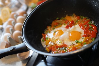 Cooking tasty eggs with vegetables in frying pan, closeup