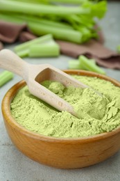 Wooden bowl and scoop with natural celery powder on grey table, closeup