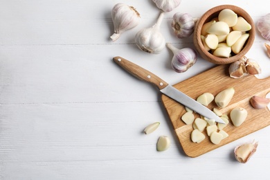 Photo of Fresh organic garlic on white wooden table, flat lay. Space for text