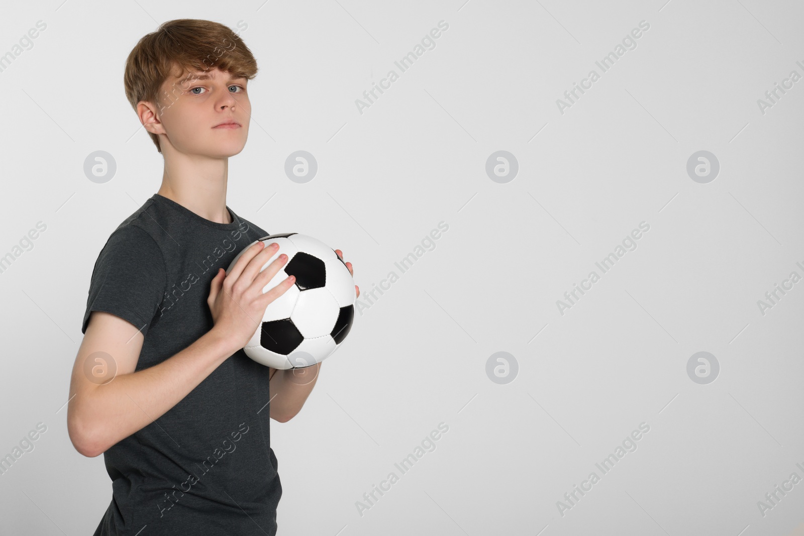 Photo of Teenage boy with soccer ball on light grey background. Space for text