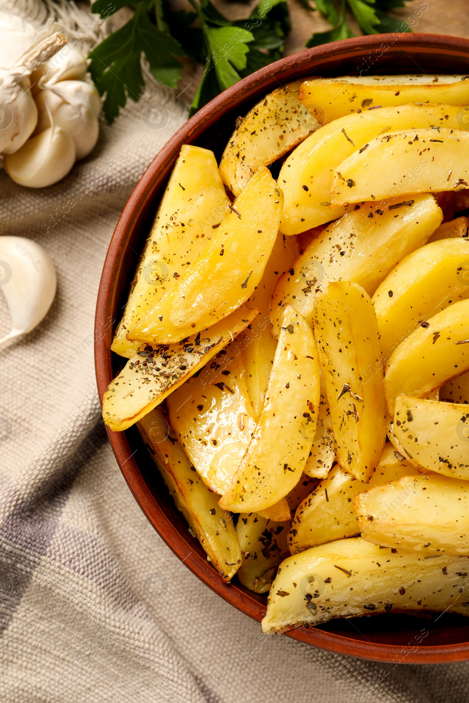 Photo of Bowl with tasty baked potato wedges and spices on table, top view