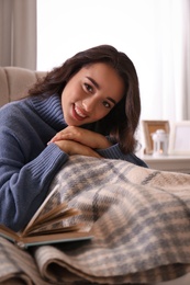 Photo of Young woman in knitted sweater resting at home. Winter atmosphere