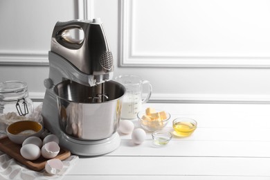 Photo of Modern stand mixer and ingredients for dough on white table indoors. Space for text