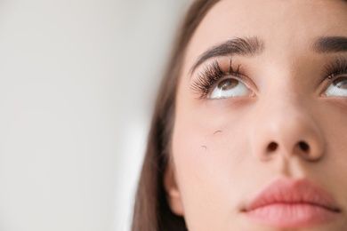 Photo of Young woman with eyelash loss problem on light background, closeup