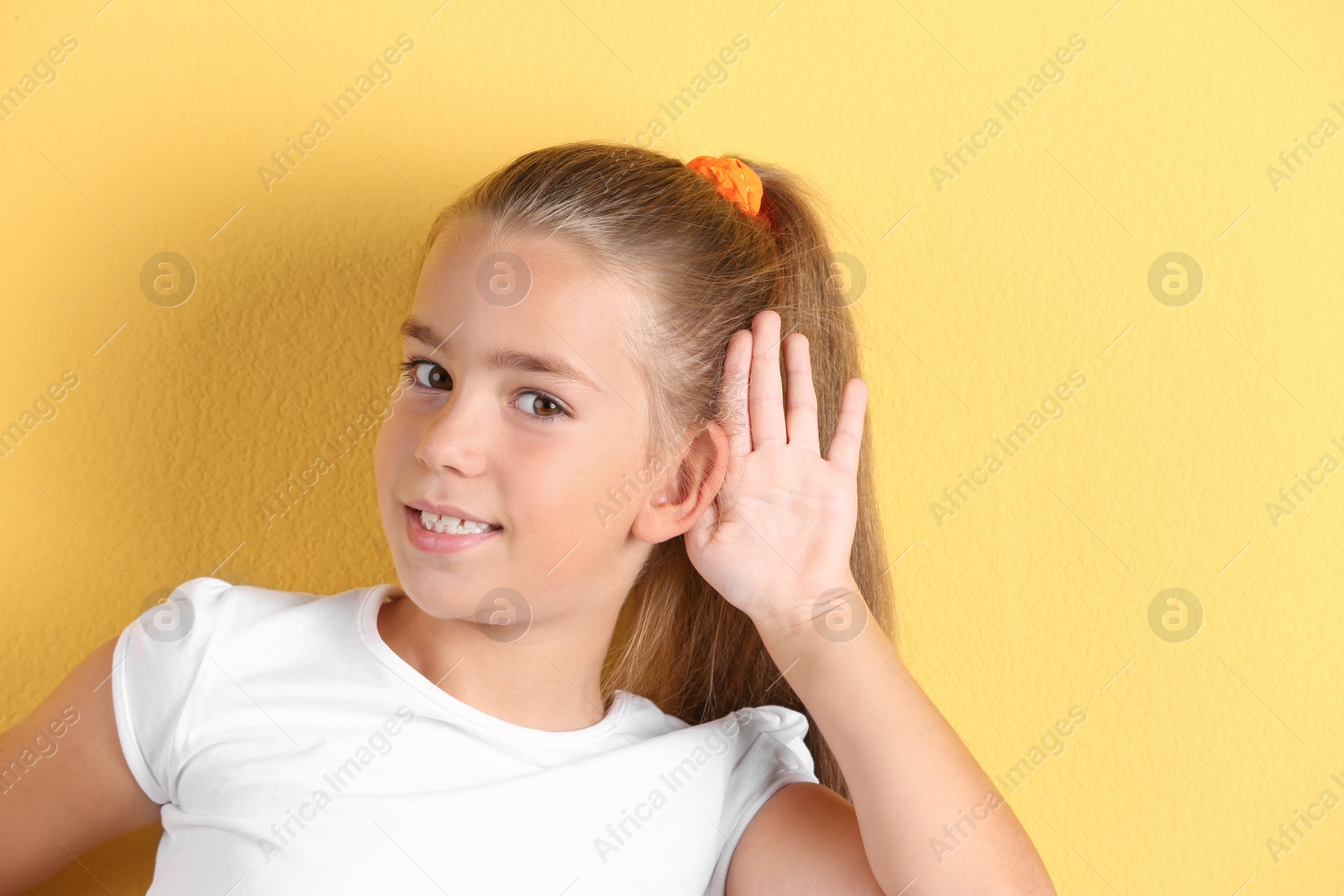 Photo of Cute little girl with hearing problem on color background