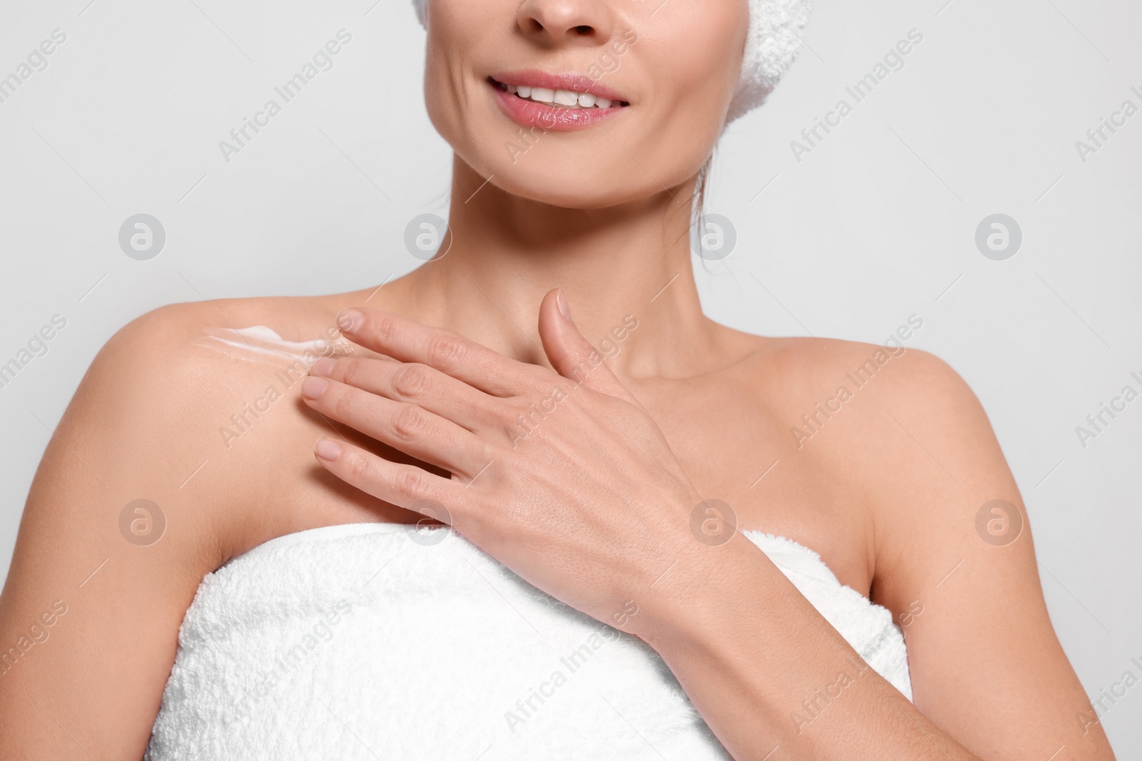 Photo of Woman applying body cream onto her collarbone against white background, closeup