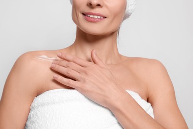 Photo of Woman applying body cream onto her collarbone against white background, closeup