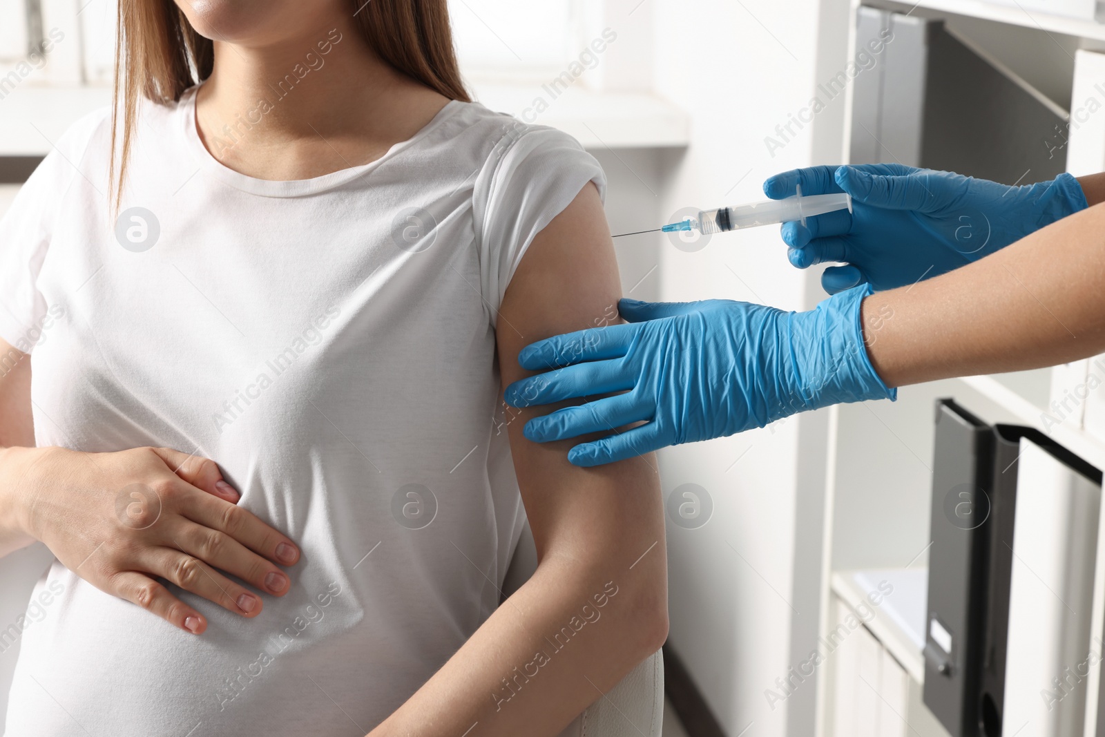 Photo of Doctor giving injection to pregnant woman in hospital, closeup