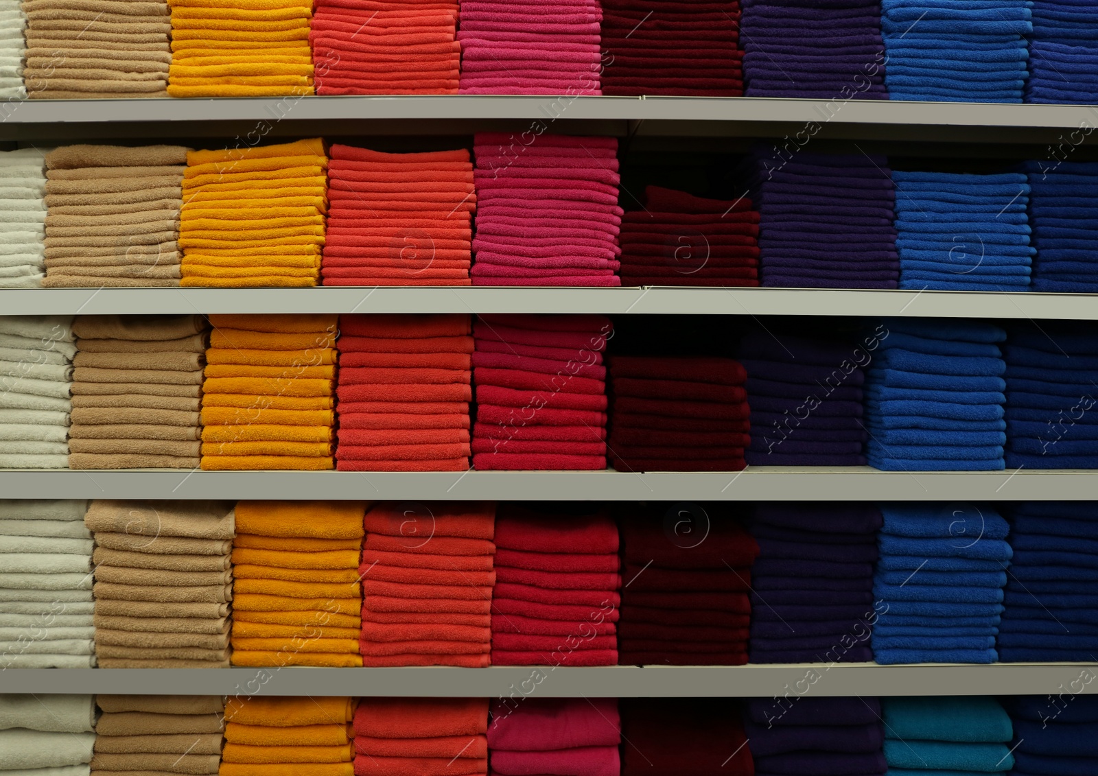 Photo of Stacks of colourful towels on store shelves