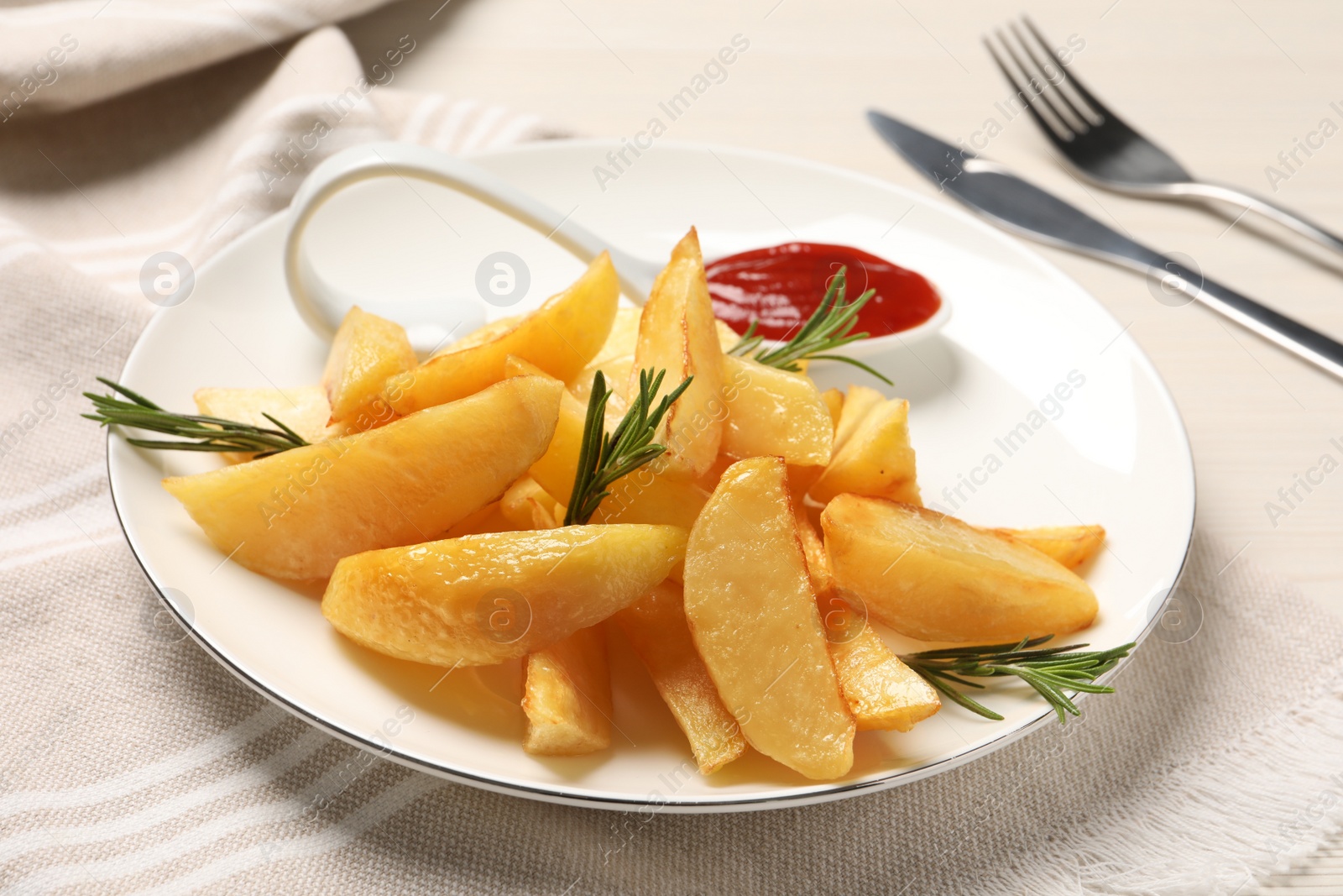 Photo of Plate with tasty baked potato wedges, rosemary and sauce on table, closeup
