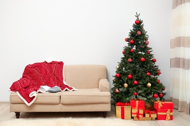 Photo of Stylish Christmas interior with decorated fir tree and comfortable sofa