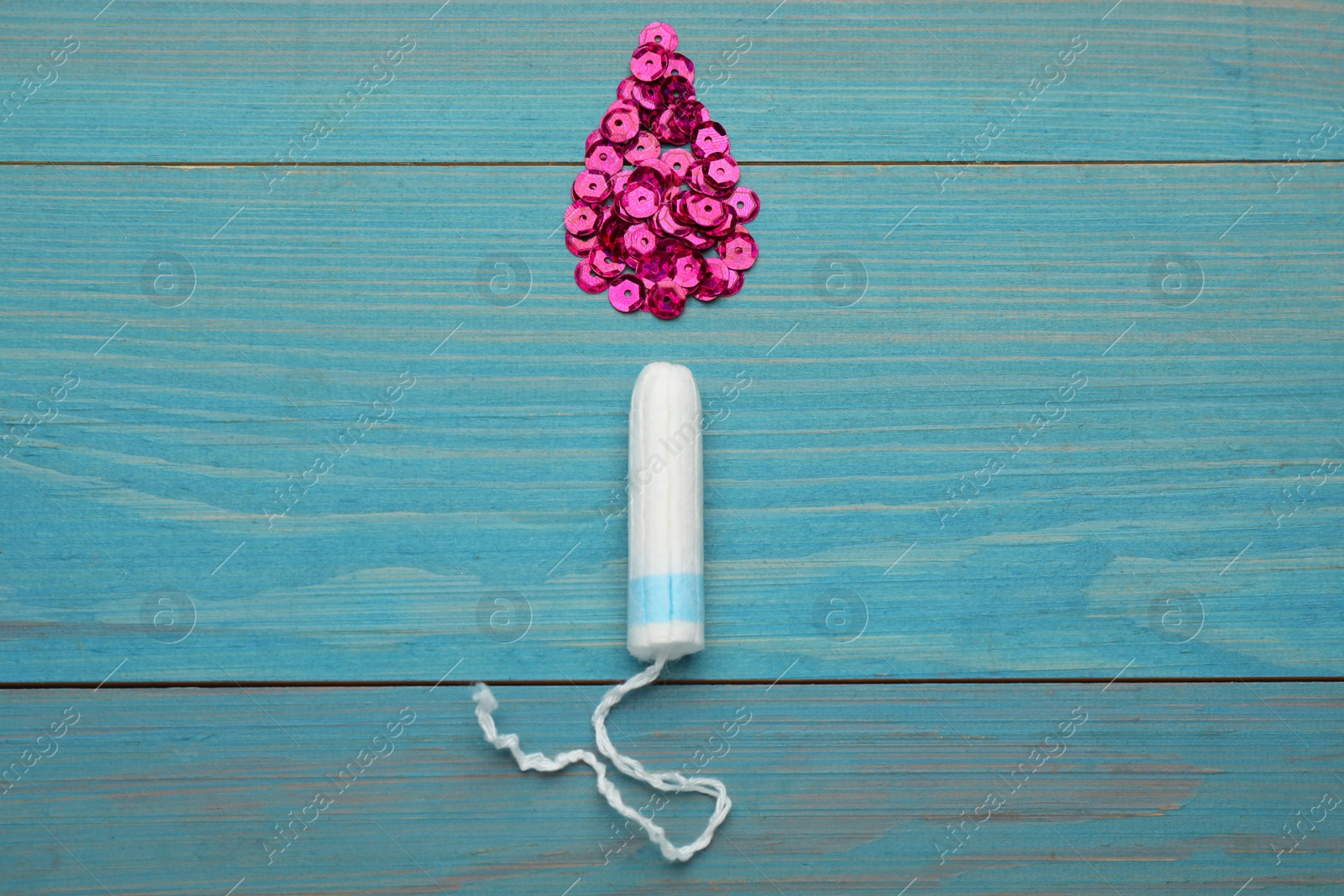 Photo of Tampon near drop made of pink sequins on turquoise wooden background, flat lay. Menstrual hygiene product