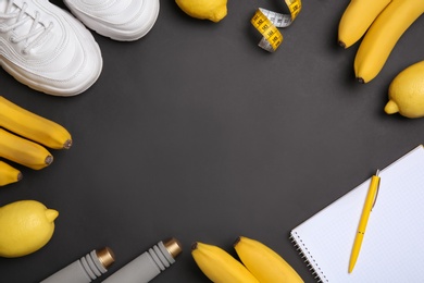 Flat lay composition with sport items, healthy food, notebook and space for text on black background. Weight loss concept