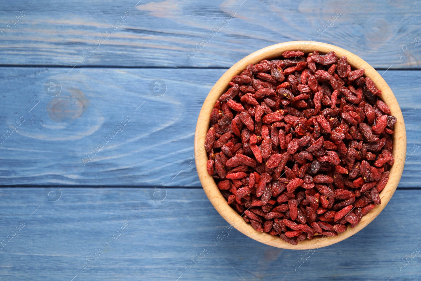 Photo of Dry goji berries on blue wooden table, top view. Space for text