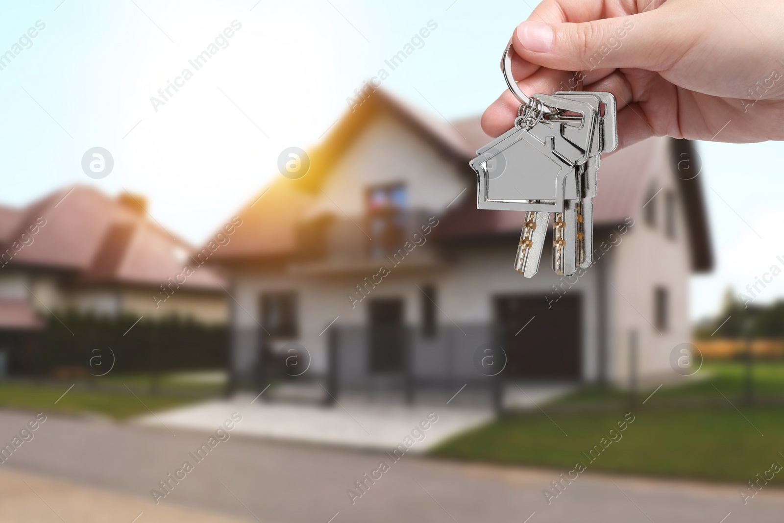 Image of Woman holding keys near house outdoors, closeup