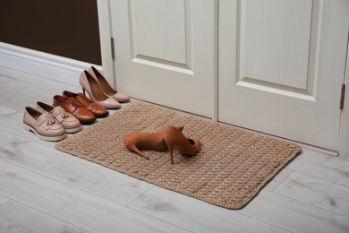 Photo of Stylish shoes and door mat in hall