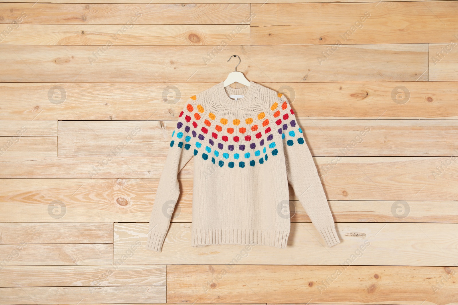 Photo of Hanger with stylish sweater on wooden background