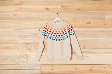 Hanger with stylish sweater on wooden background