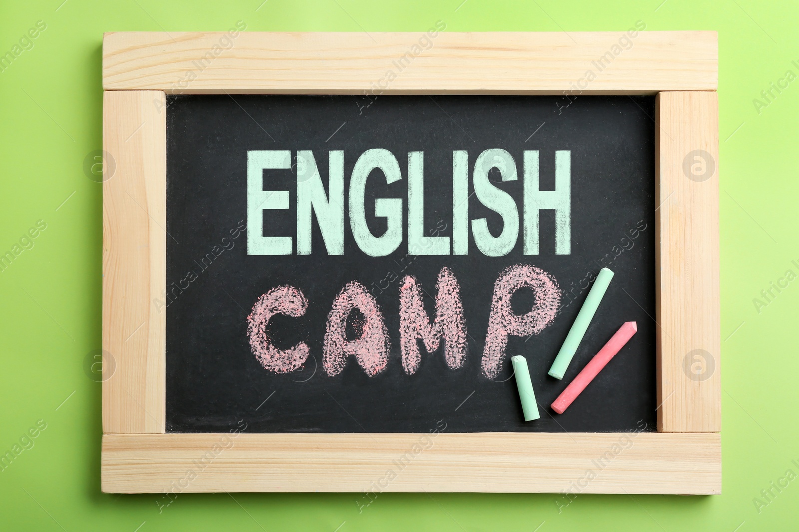 Image of Words ENGLISH CAMP on small blackboard and colorful chalk, top view