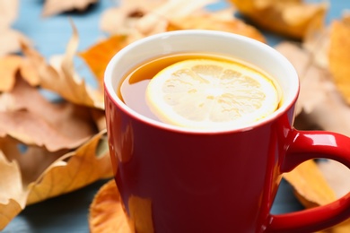 Photo of Cup of hot drink and leaves on table, closeup. Cozy autumn atmosphere
