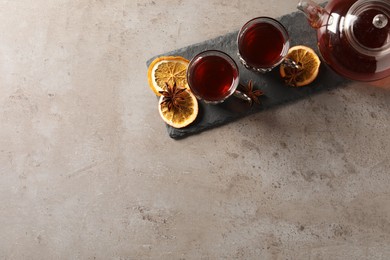 Slate plate with glasses of traditional Turkish tea in vintage holders, pot, dried orange and anise on light grey table, top view. Space for text