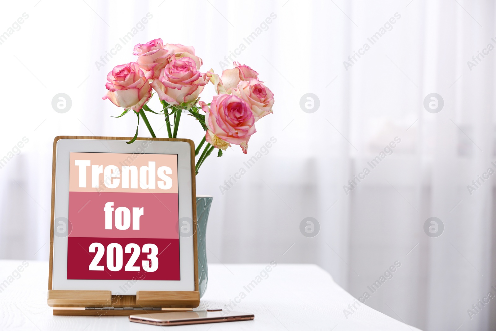 Image of Trends For 2023 text on tablet display. Device, phone and flowers on white table, space for text