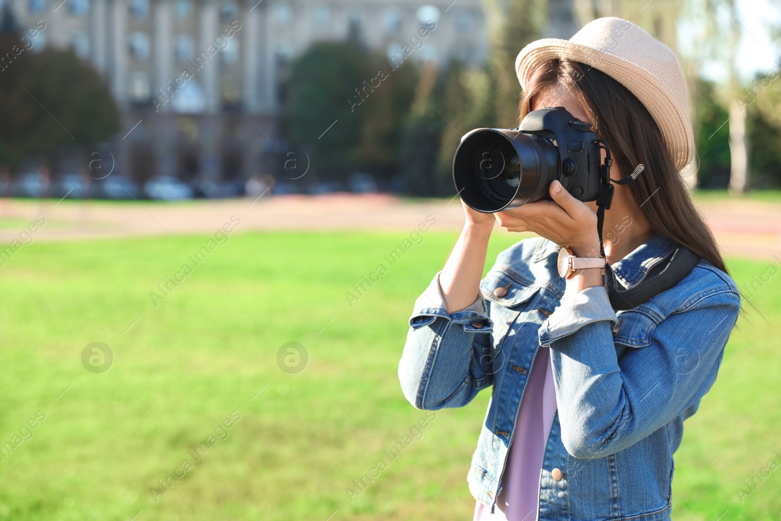 Photo of Young female photographer taking photo with professional camera on street. Space for text