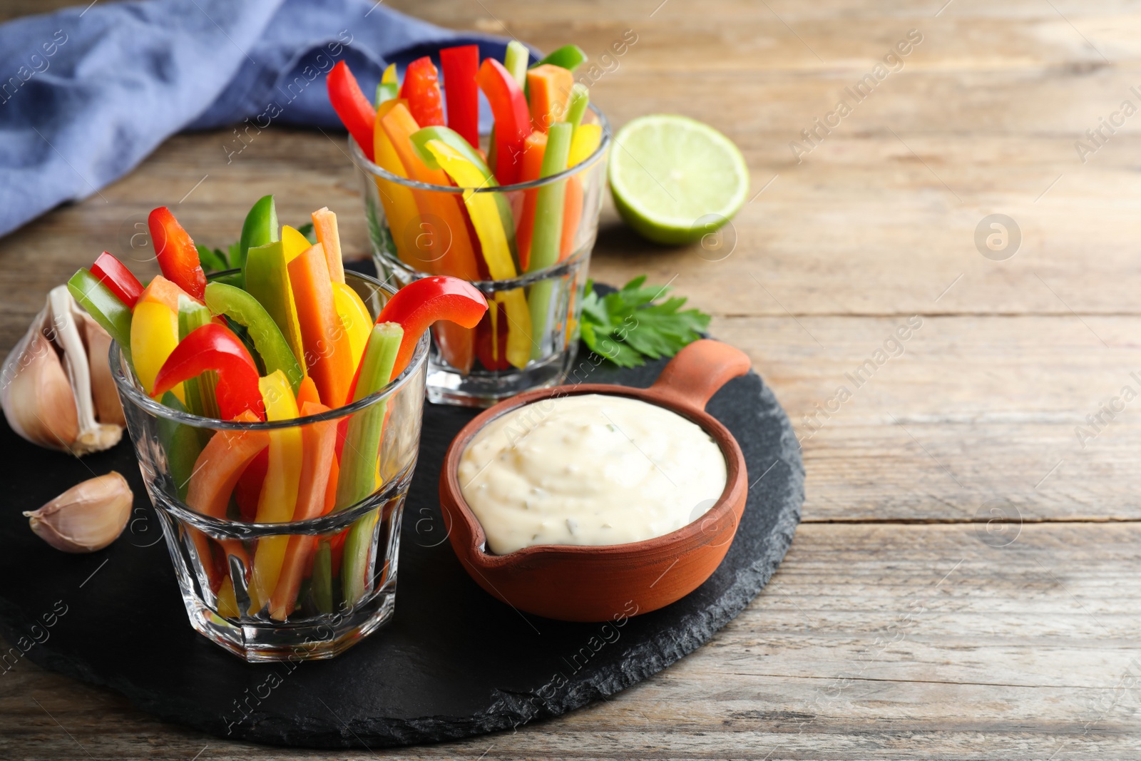 Photo of Fresh raw vegetable sticks and sauce on wooden table