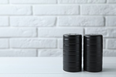 Photo of Salt and pepper shakers on white wooden table. Space for text