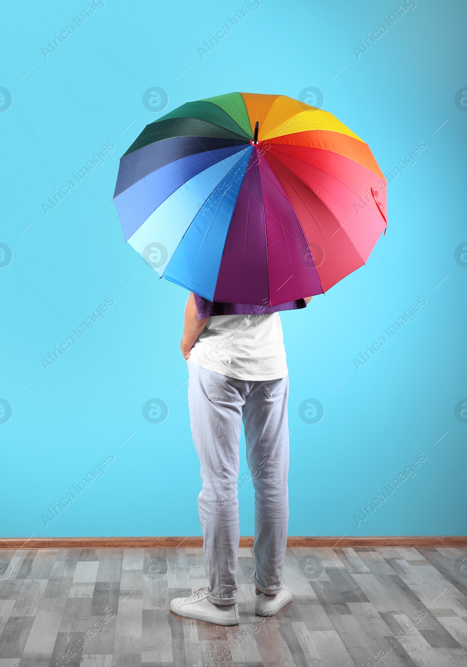 Photo of Man with rainbow umbrella near color wall