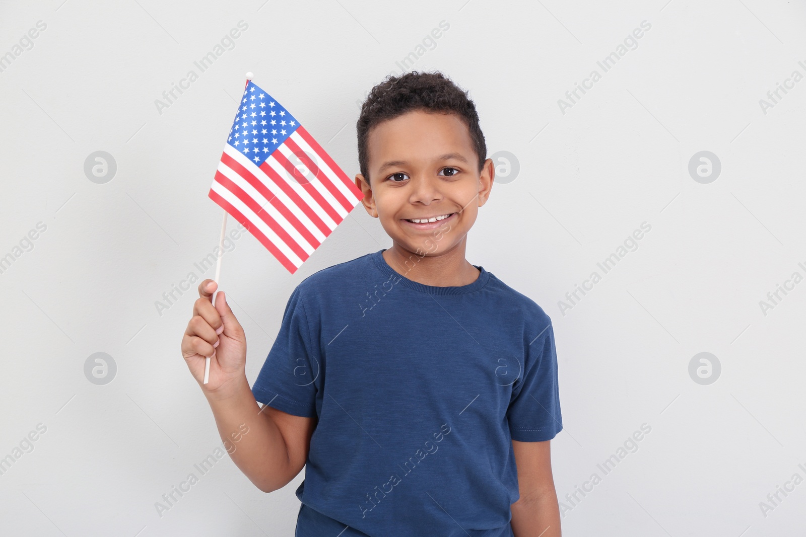 Photo of Happy African-American boy holding national flag on light background