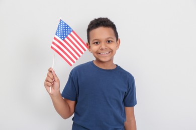 Photo of Happy African-American boy holding national flag on light background