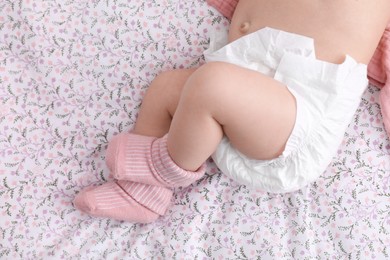 Little baby in diaper on bed, top view