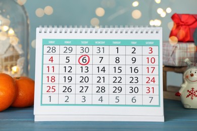 Photo of Saint Nicholas Day. Calendar with marked date December 06, tangerines and festive decor on turquoise wooden table against blurred lights