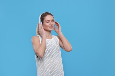 Sportswoman with headphones on light blue background, space for text