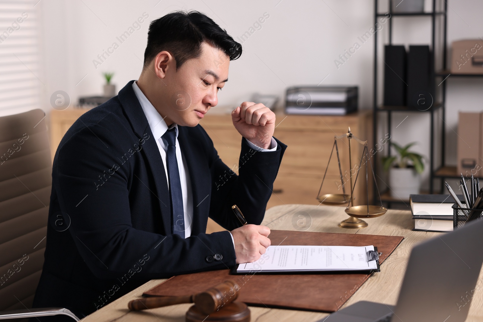 Photo of Notary writing notes at wooden table in office