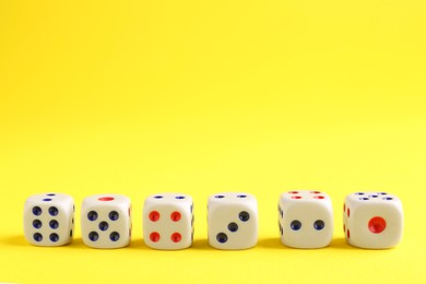 Photo of Many white game dices on yellow background. Space for text