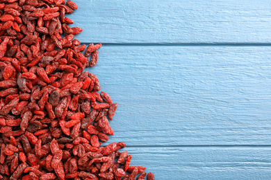 Photo of Dried goji berries on blue wooden table, top view. Space for text