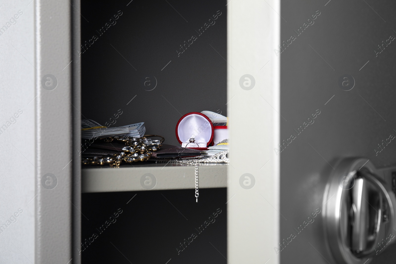 Open steel safe with money and jewelry, closeup Photo of Open steel safe with money and jewelry, closeup