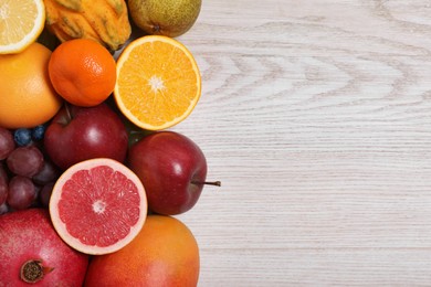 Photo of Many different fresh fruits on light wooden table, flat lay. Space for text