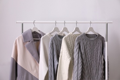 Rack with stylish warm clothes in room