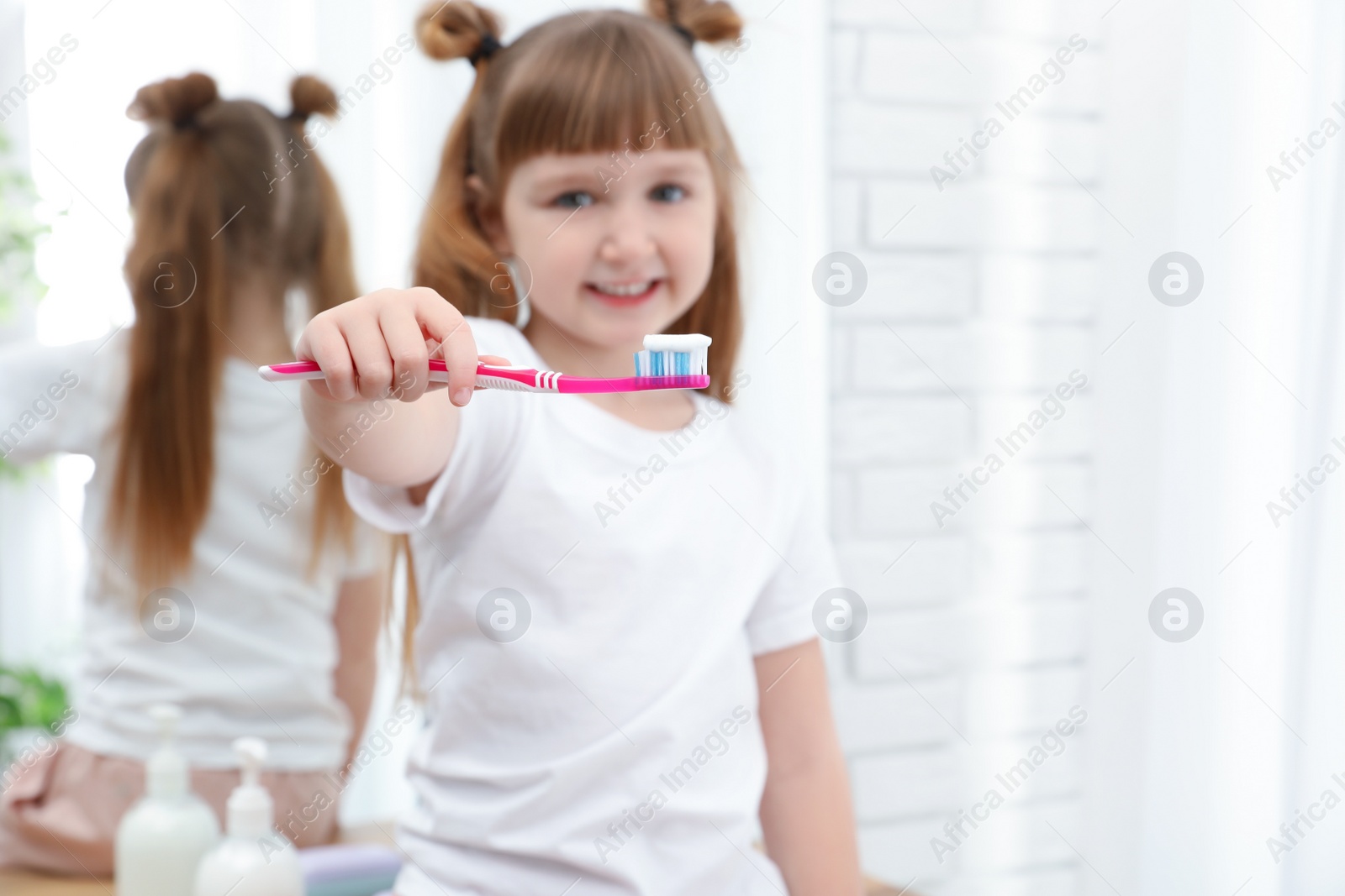 Photo of Little girl brushing teeth in bathroom at home. Space for text