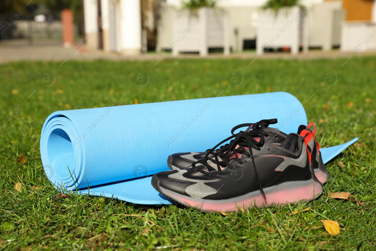 Photo of Bright karemat or fitness mat and sportive shoes on fresh green grass outdoors